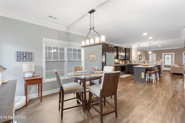 dining space featuring wood-type flooring, ornamental molding, and a chandelier