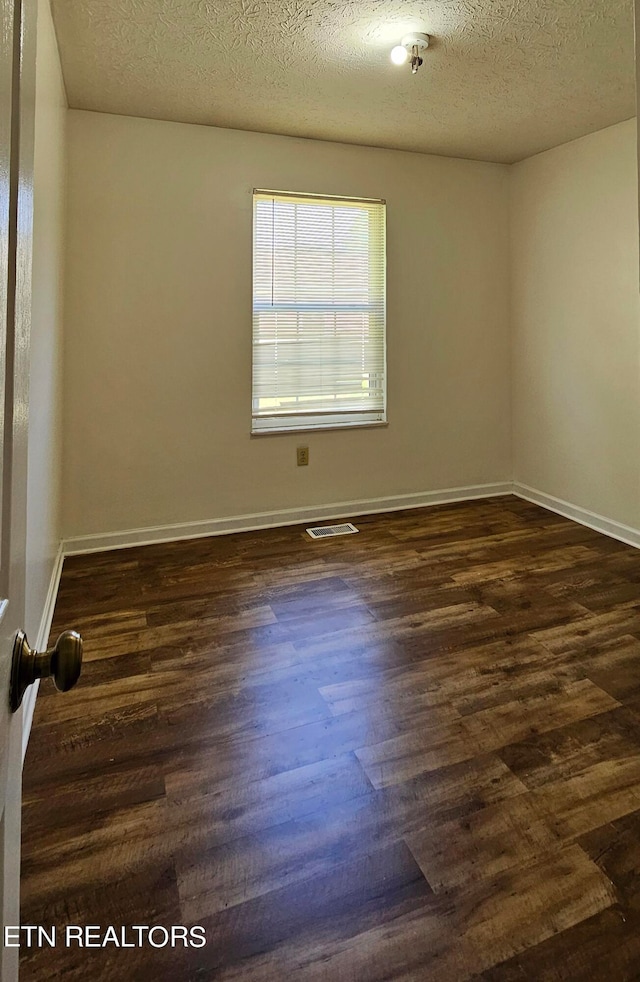 unfurnished room with a textured ceiling and dark hardwood / wood-style floors