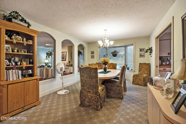 dining room with arched walkways, carpet flooring, a textured ceiling, and a chandelier