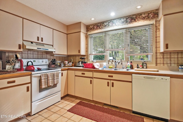 kitchen featuring light tile patterned floors, white appliances, a textured ceiling, and a healthy amount of sunlight