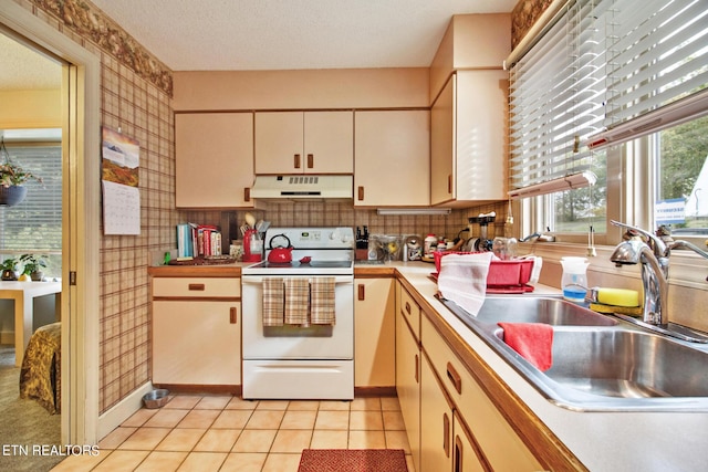 kitchen featuring electric range, light countertops, under cabinet range hood, a sink, and light tile patterned floors