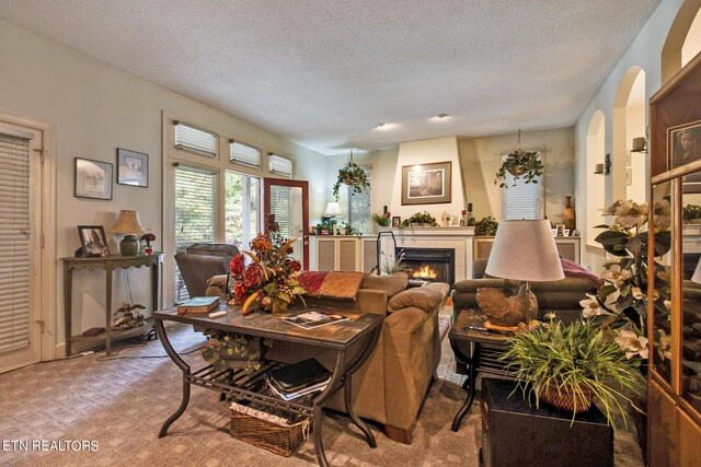 carpeted living room featuring a tiled fireplace and a textured ceiling