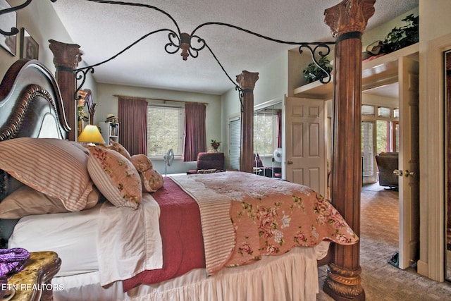 bedroom featuring multiple windows, carpet, and a textured ceiling