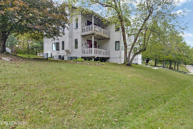 back of house featuring a balcony, central AC unit, and a yard