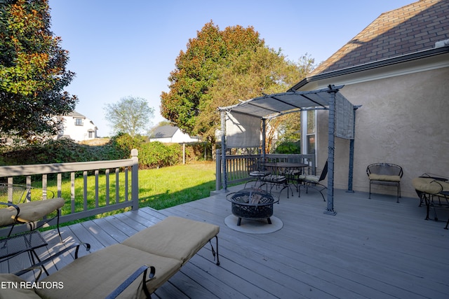 wooden deck with an outdoor fire pit and a lawn