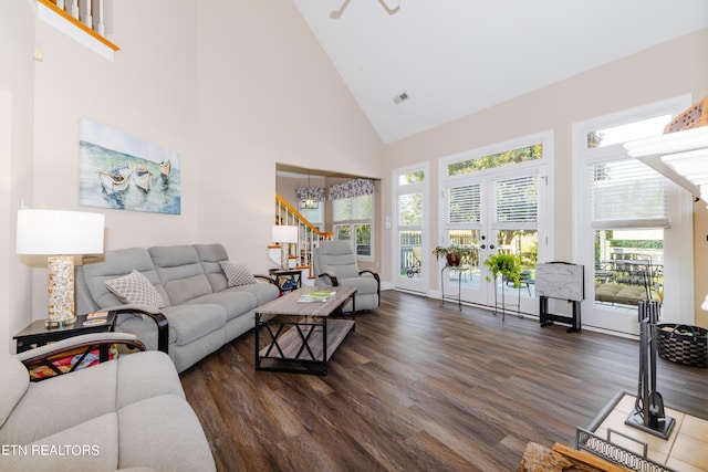 living room with a wealth of natural light, a notable chandelier, high vaulted ceiling, and dark hardwood / wood-style flooring