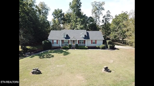 cape cod-style house with a front yard and a fire pit