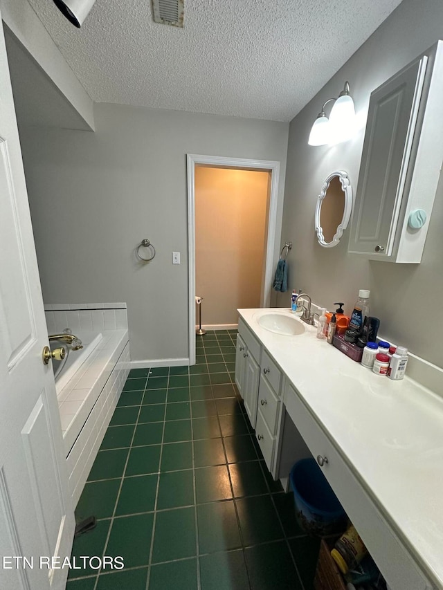 bathroom with vanity, a textured ceiling, tiled tub, and tile patterned flooring