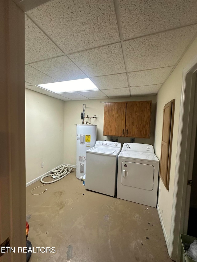 clothes washing area featuring cabinets, water heater, and washer and clothes dryer