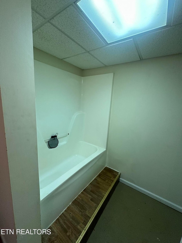 bathroom with a drop ceiling, wood-type flooring, and a washtub