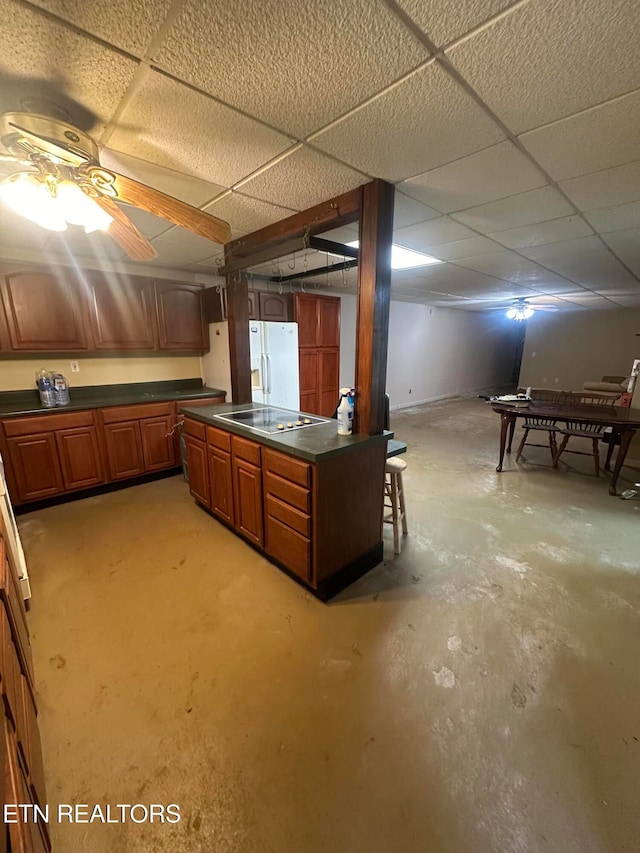 basement featuring a drop ceiling, ceiling fan, and white fridge with ice dispenser