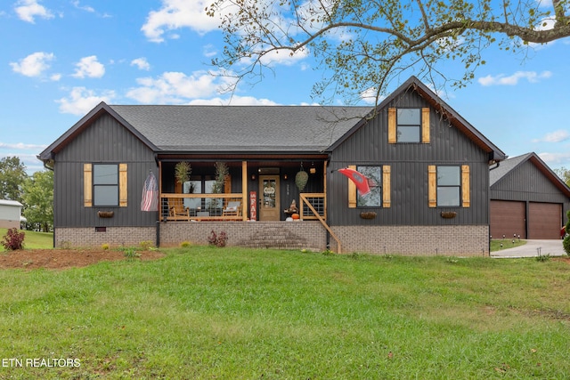 view of front of home featuring covered porch, a garage, a front lawn, and an outdoor structure