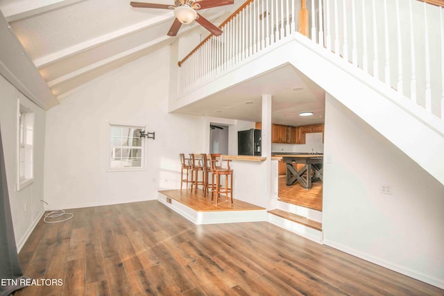 unfurnished living room featuring high vaulted ceiling, wood-type flooring, ceiling fan, and beam ceiling