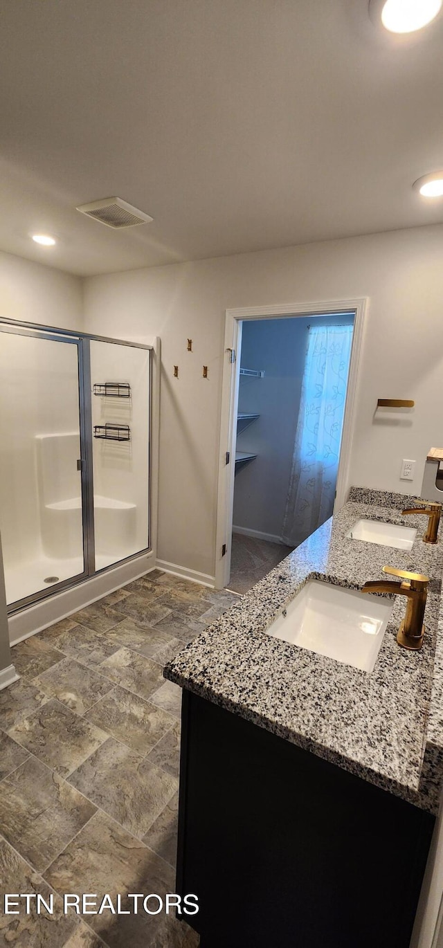 bathroom featuring a shower with door and vanity