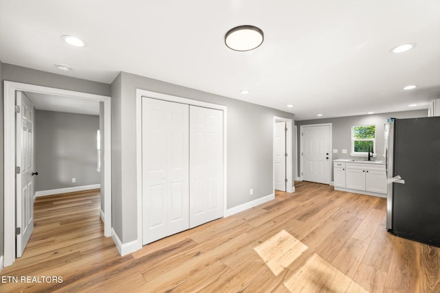 kitchen with white cabinets, stainless steel fridge, light wood-type flooring, and sink