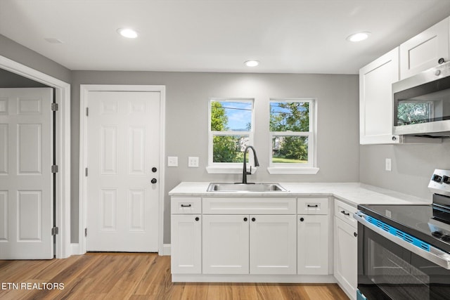 kitchen with light hardwood / wood-style flooring, white cabinets, appliances with stainless steel finishes, and sink