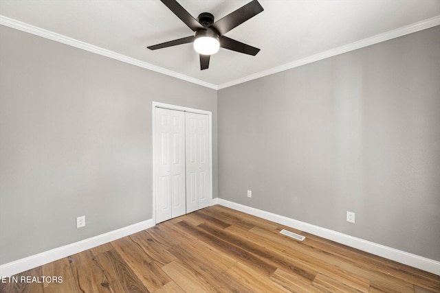 unfurnished bedroom featuring ornamental molding, ceiling fan, a closet, and hardwood / wood-style floors