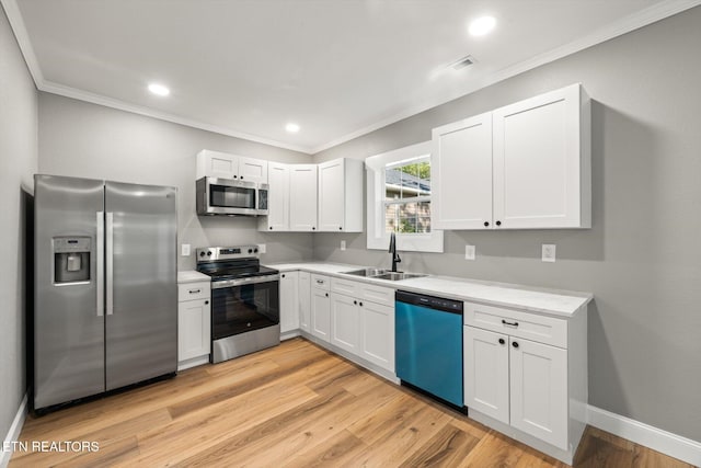 kitchen with ornamental molding, sink, light hardwood / wood-style flooring, white cabinetry, and appliances with stainless steel finishes