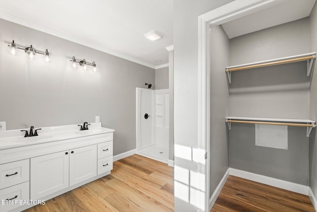 bathroom with wood-type flooring, ornamental molding, and vanity