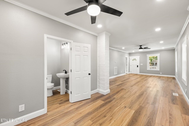 unfurnished living room with crown molding, sink, light wood-type flooring, and ceiling fan