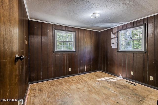 unfurnished room with hardwood / wood-style flooring, wooden walls, and a textured ceiling