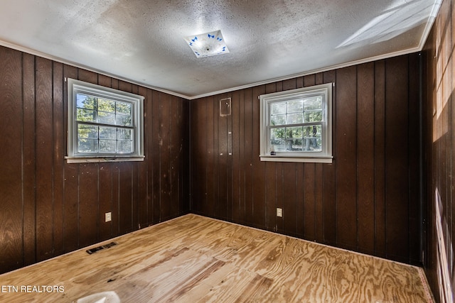 spare room with wood-type flooring, wooden walls, and a textured ceiling