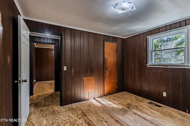 unfurnished bedroom featuring a closet, hardwood / wood-style flooring, wooden walls, and a textured ceiling