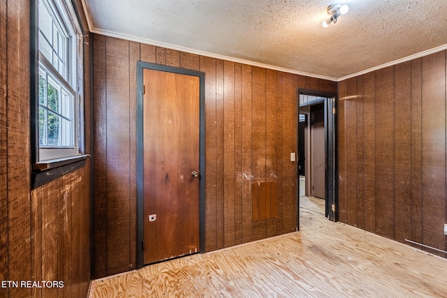 interior space featuring crown molding, wood walls, a closet, and light hardwood / wood-style floors