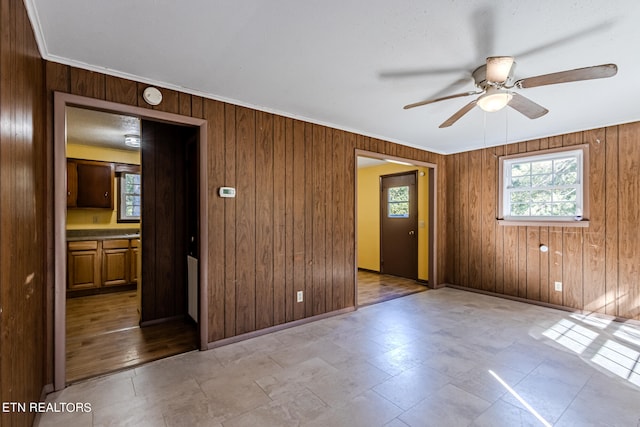 spare room with ornamental molding, ceiling fan, and wood walls