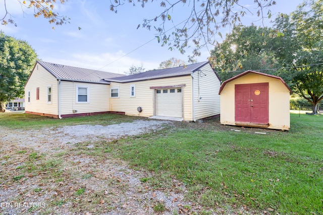 back of house featuring a garage, a shed, and a yard