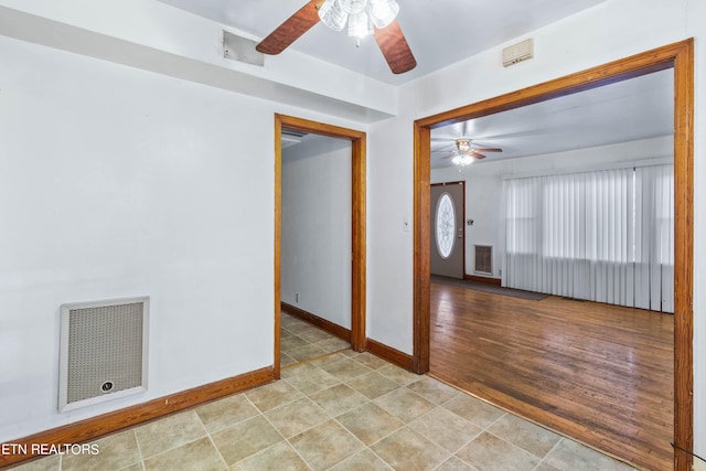 empty room featuring light wood-type flooring, ceiling fan, and heating unit