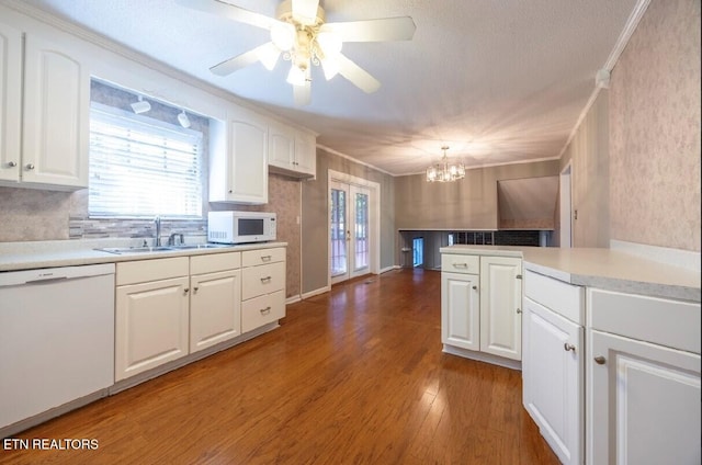 kitchen featuring hardwood / wood-style flooring, sink, decorative light fixtures, white cabinets, and white appliances