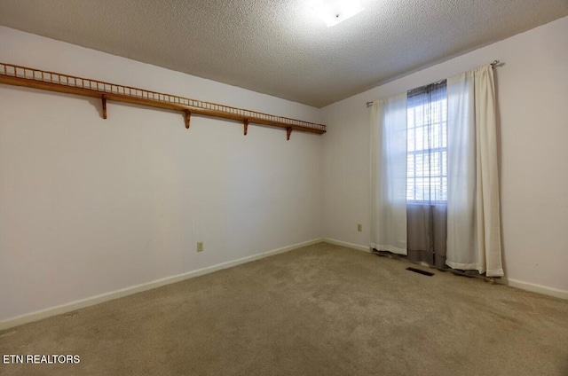 spare room featuring a textured ceiling and light colored carpet