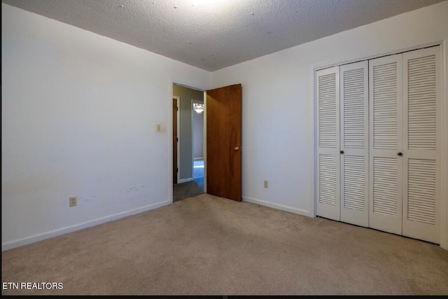 unfurnished bedroom featuring a textured ceiling, light colored carpet, and a closet