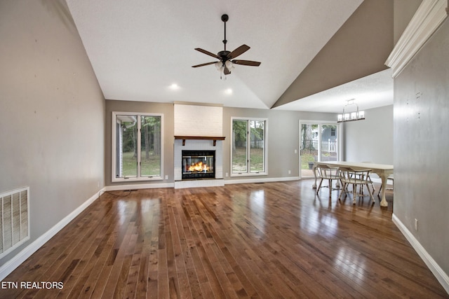 unfurnished living room with a healthy amount of sunlight, ceiling fan, a large fireplace, and dark hardwood / wood-style flooring