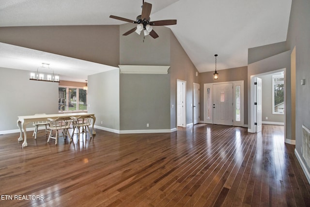 unfurnished living room featuring ceiling fan with notable chandelier, high vaulted ceiling, and dark hardwood / wood-style flooring