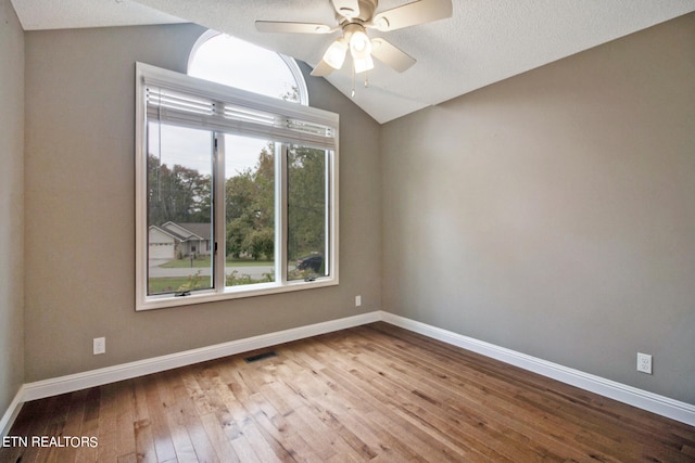 empty room featuring lofted ceiling, ceiling fan, light hardwood / wood-style floors, and a textured ceiling