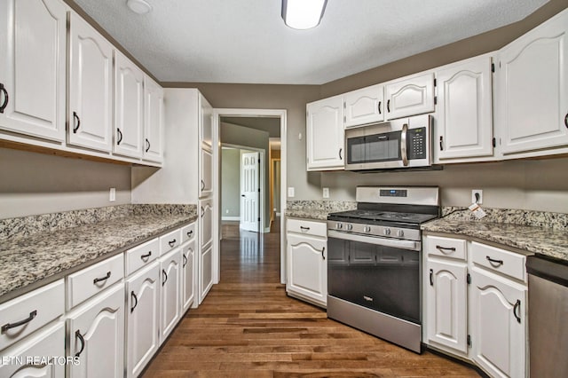 kitchen featuring light stone countertops, dark wood-type flooring, stainless steel appliances, and white cabinets