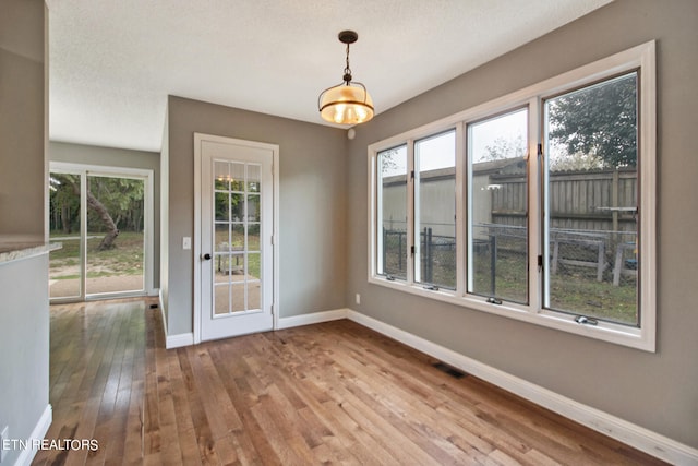 unfurnished dining area with hardwood / wood-style flooring and a textured ceiling