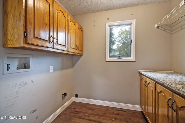 laundry area featuring hookup for a washing machine, cabinets, dark hardwood / wood-style floors, and a textured ceiling