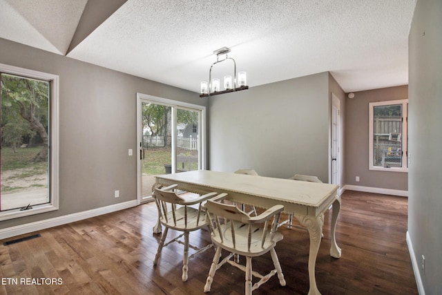 dining room with dark hardwood / wood-style floors, an inviting chandelier, and a textured ceiling