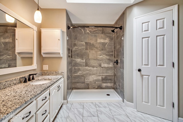 bathroom featuring tiled shower and vanity