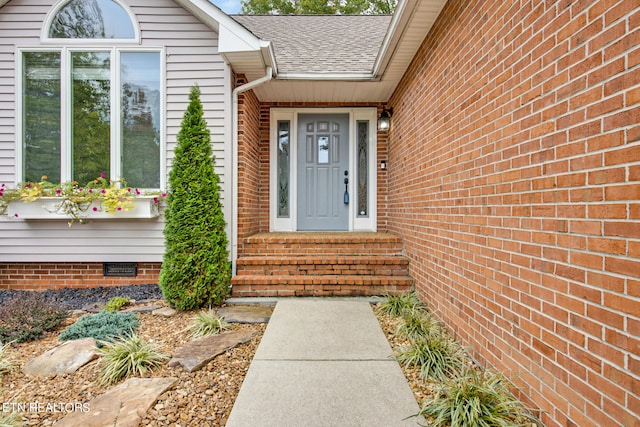 entrance to property with crawl space, roof with shingles, and brick siding