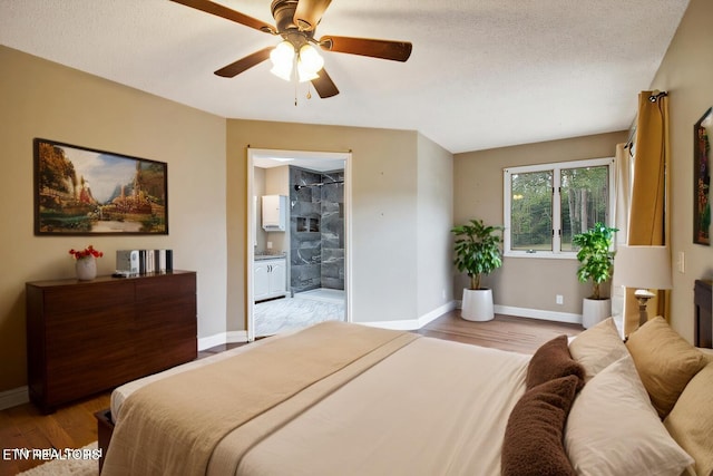 bedroom with ensuite bathroom, a textured ceiling, light wood-style flooring, and baseboards