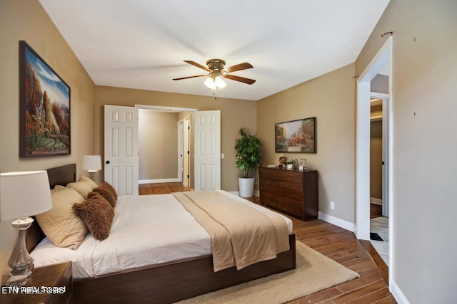 bedroom with dark wood-style flooring, a ceiling fan, and baseboards