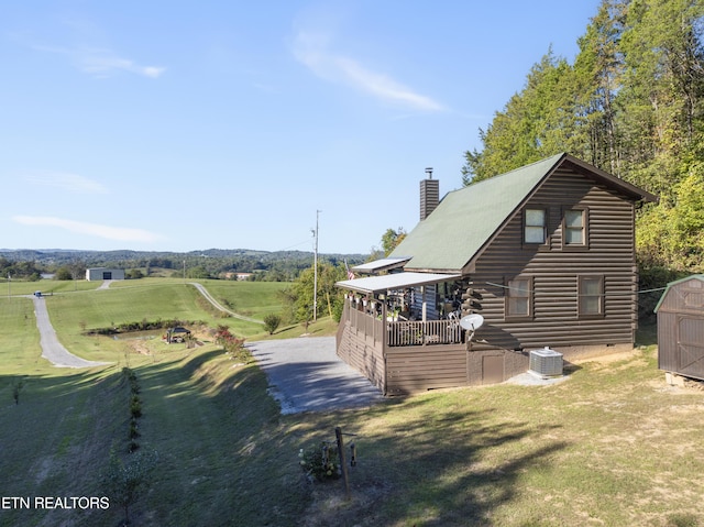 rear view of property with a lawn, central AC, and a storage shed