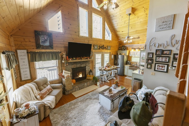 living room featuring ceiling fan, wood walls, wood ceiling, and high vaulted ceiling