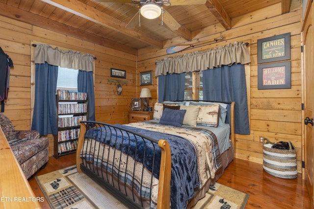 bedroom featuring hardwood / wood-style floors, wood walls, wooden ceiling, ceiling fan, and beamed ceiling