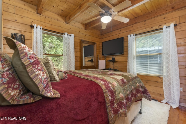 bedroom featuring beamed ceiling, ceiling fan, wooden walls, and wood ceiling