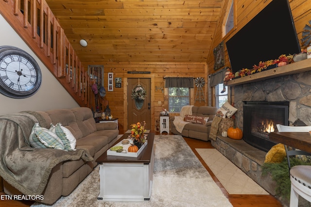 living room featuring wood walls, high vaulted ceiling, light wood-type flooring, a fireplace, and wood ceiling